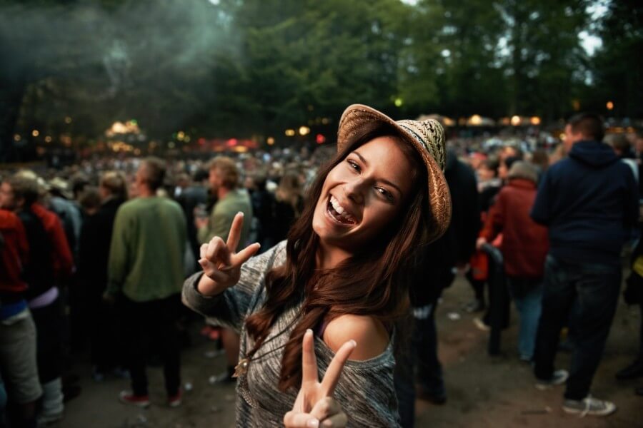 girl smiling and waving peace sign at a festival
