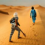 Desert blues, guitarists walking along a dune