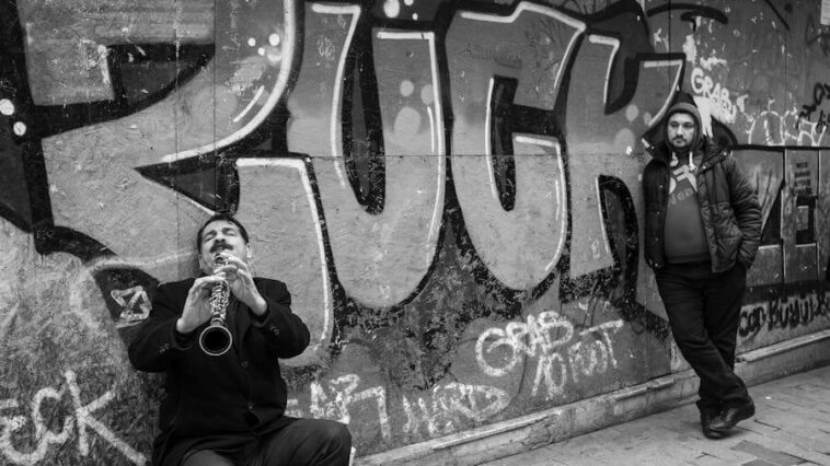 Street busker being observed with graffiti on the wall