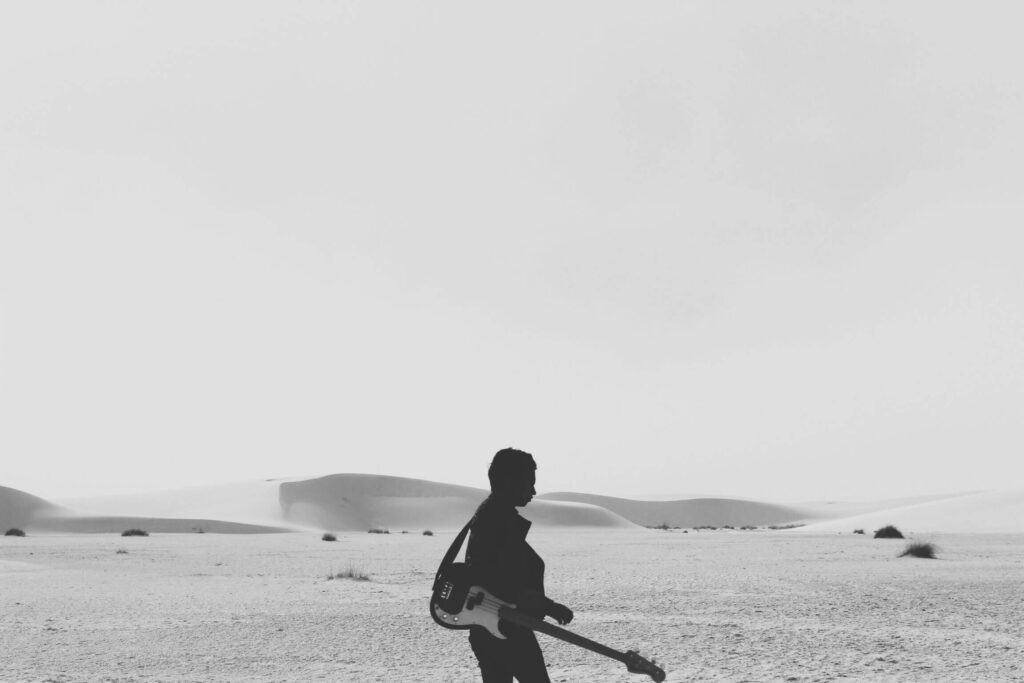 Person holding guitar in desert