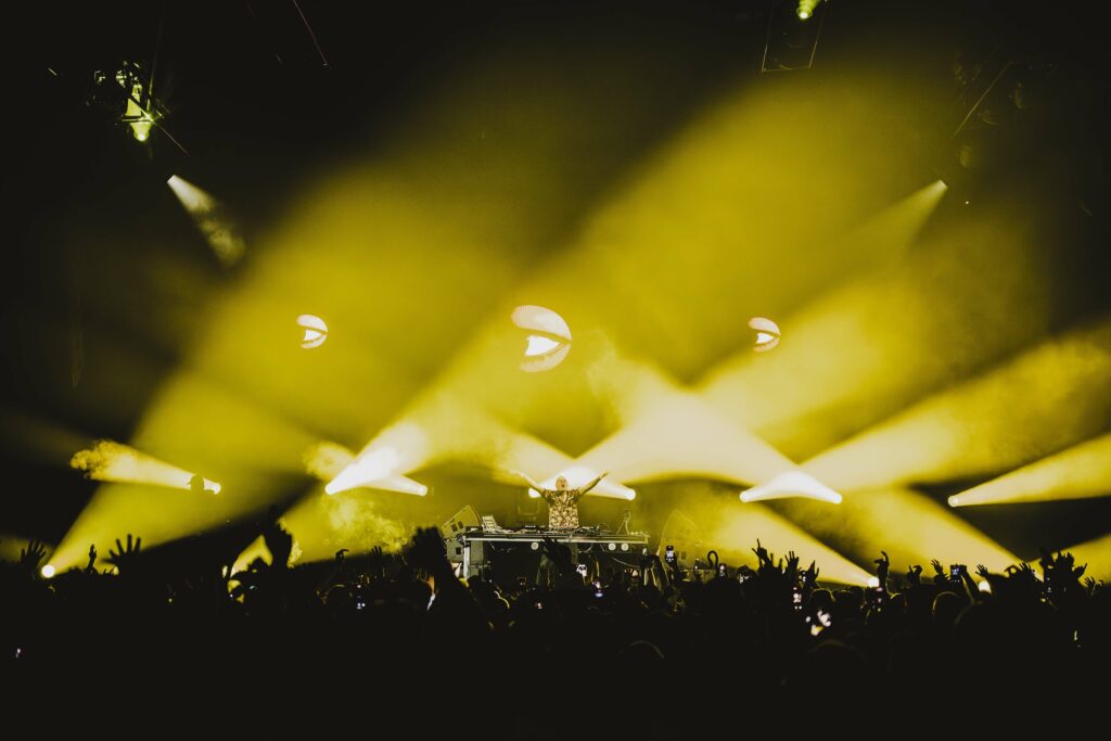 View facing the stage from the back at a Fatboy Slim set with yellow lights.