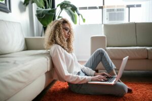 Woman working on her laptop, sitting on the floor