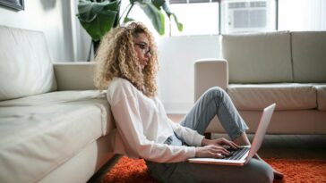 Woman working on her laptop, sitting on the floor