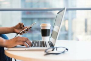 Worker on their laptop with glasses and coffee in the image