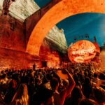 DJ playing in front of the Valetta battlements with orange lighting.