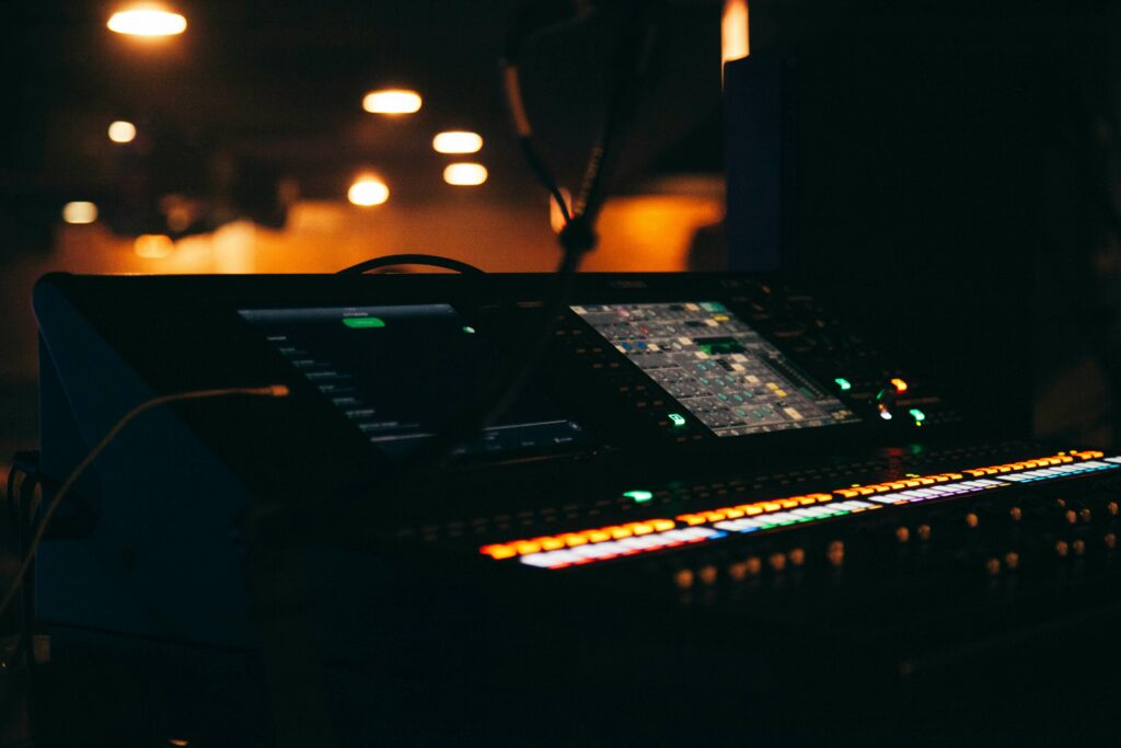 Dark music recording studio with two screens and illuminated buttons.