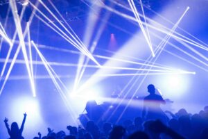 DJ set with blue and white lighting, people raising their arms.