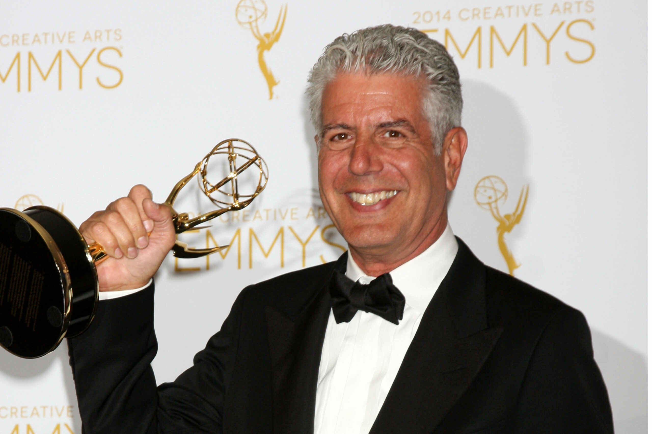 Photo of Anthony Bourdain in a tux holding a grammy award.